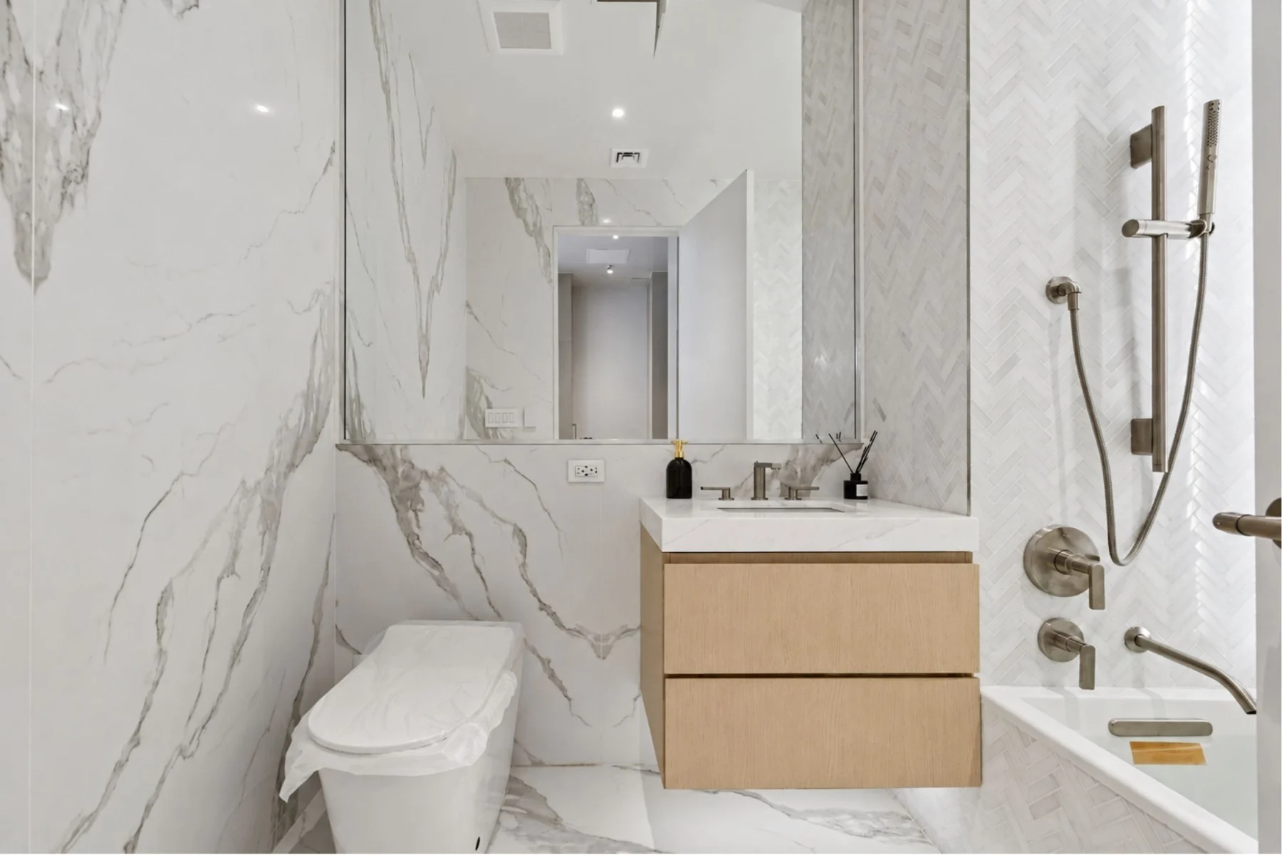 The Icon condominium bathroom in Long Island City, with floating vanity, mirrored cabinet and bathtub with shower